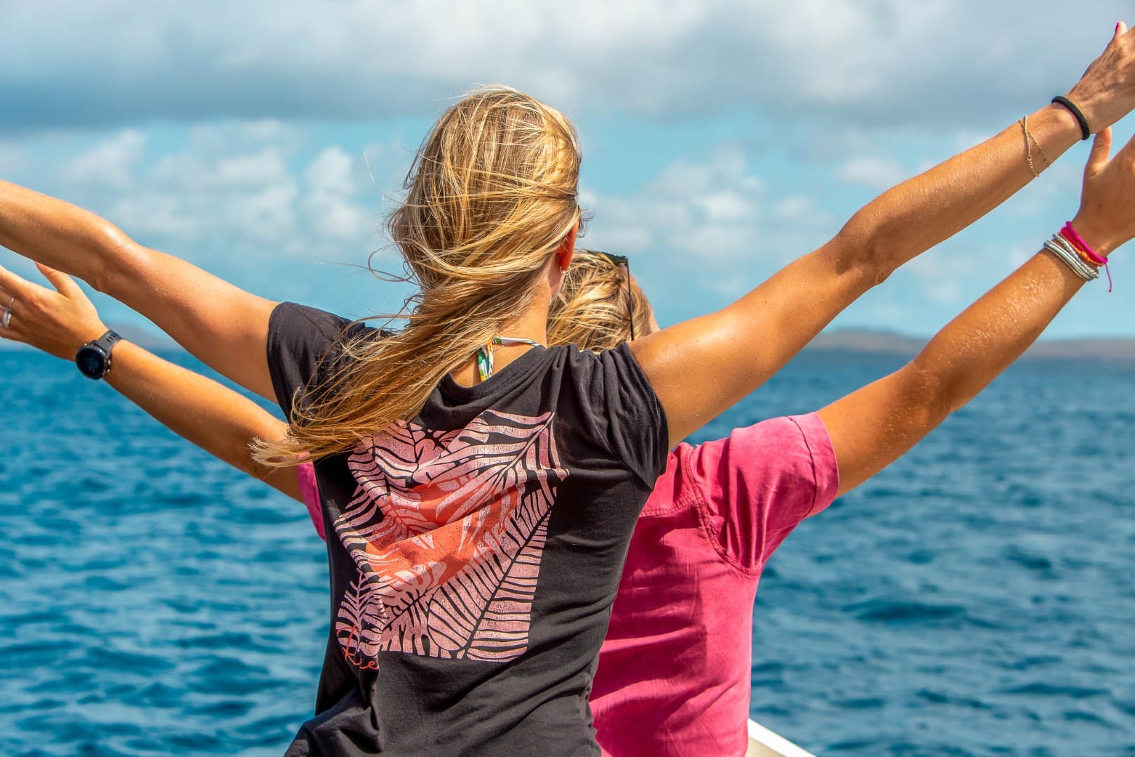 Two guests with arms spread enjoying the water on Bonaire